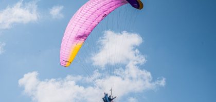 Experience the thrill of tandem paragliding with colorful parachute soaring high in the clear blue sky.