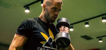 Muscular man exercising with a dumbbell in a modern gym setting, emphasizing strength and fitness.